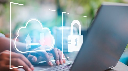 A person is typing on an open laptop. Two icons can be seen in a semi-transparent graphic. One of them shows a cloud with an upload or download symbol. The other icon shows a lock, which stands for data security.